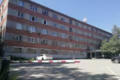 Общежитие №16А ИРНИТУ на Лермонтова, 102а — пятиэтажный корпус с красно-серым полосатым фасадом, перед входом шлагбаум и парковка