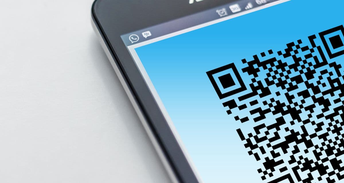 Угол чёрного смартфона на светло-сером фоне, на экране крупный QR-код на голубом градиенте