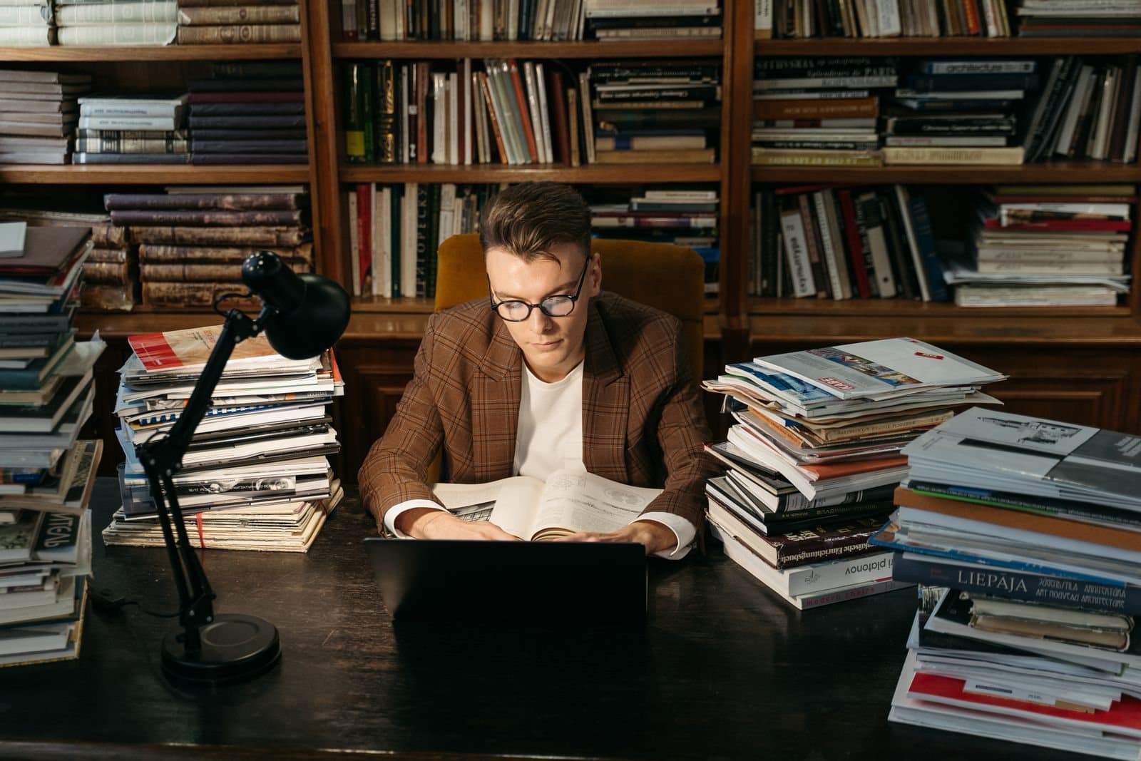 Работа за ноутбуком среди стопок книг в библиотеке