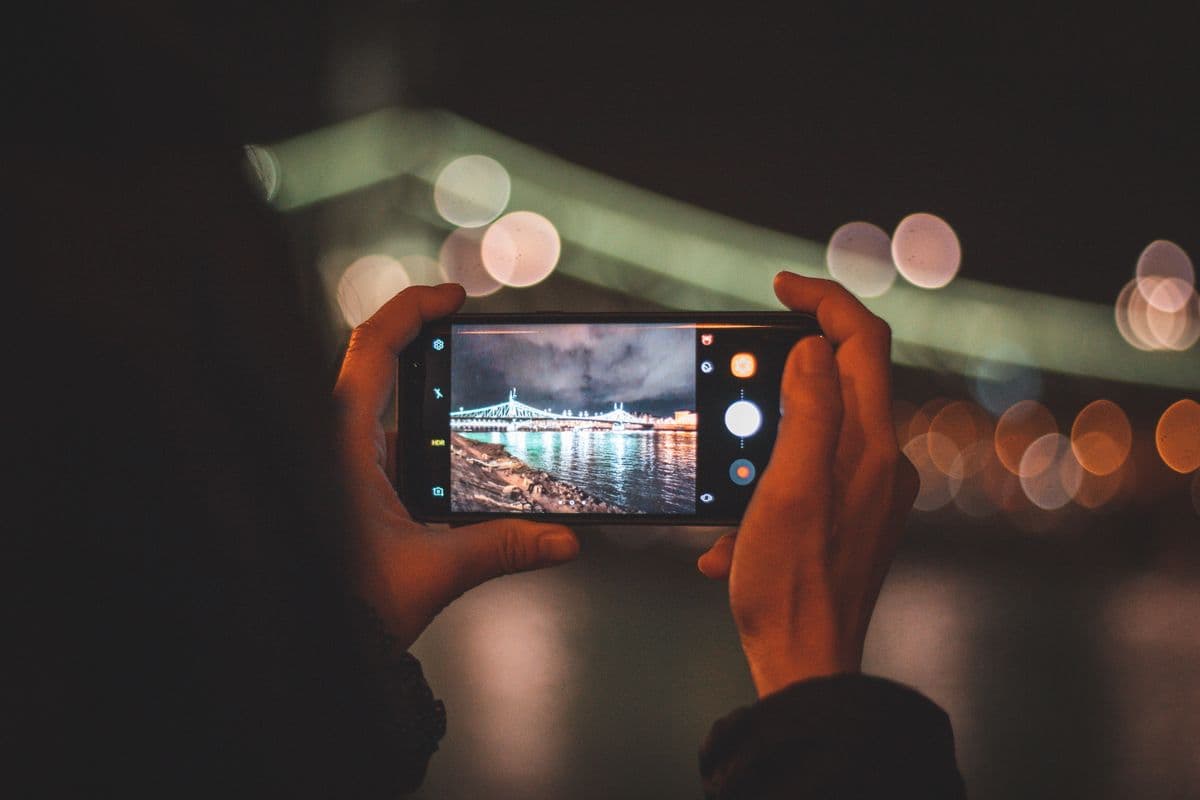 Девушка фотографирует на смартфон, рядом разложены распечатанные снимки