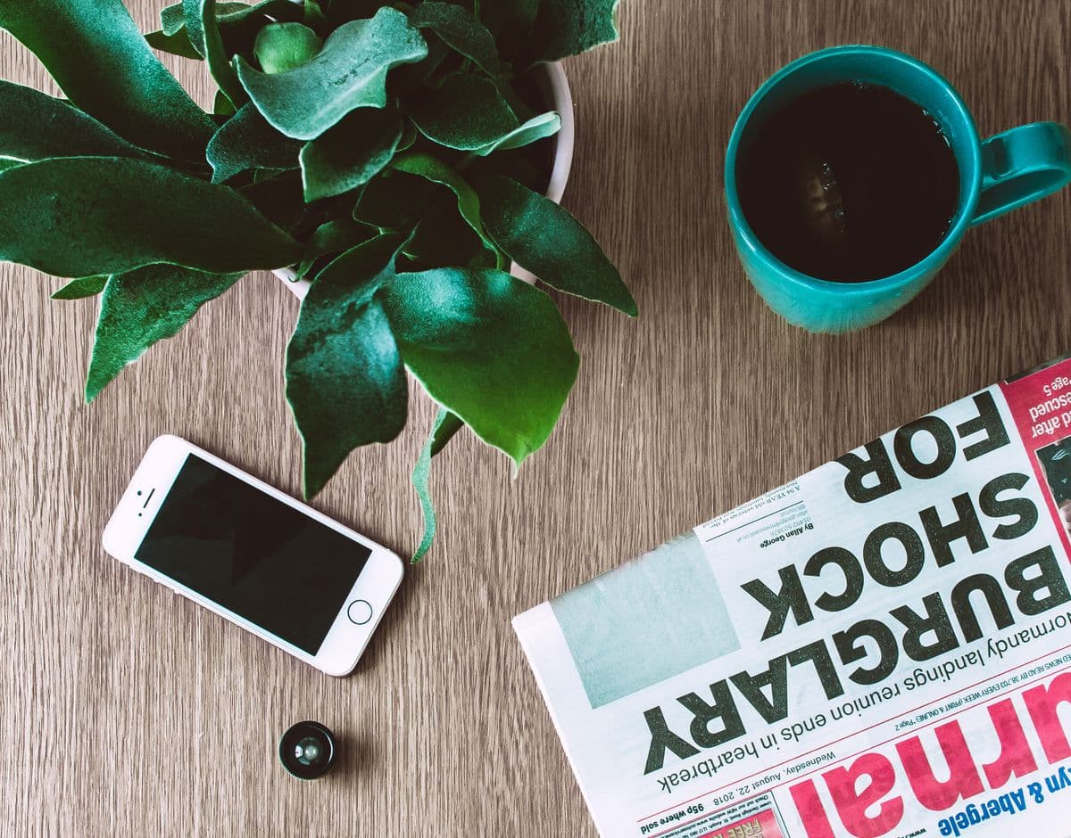 Человек читает ленту новостей на смартфоне и ноутбуке за столом