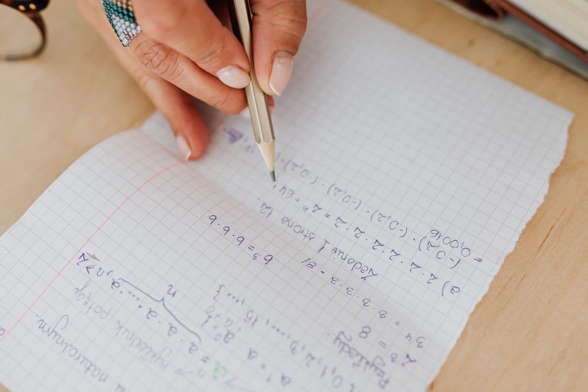 Тетрадь в клетку с примерами на корни и степени, карандаш