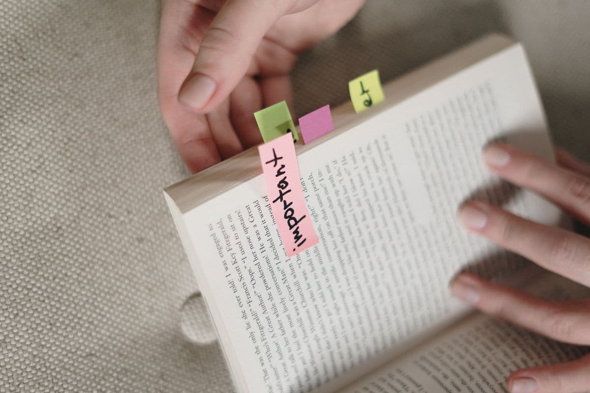 Руки держат открытую книгу с цветными стикерами-закладками, на розовом стикере написано Important